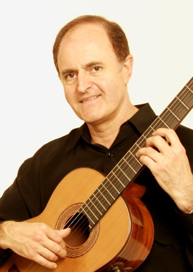 Close-up of Julian Byzantine smiling with his guitar, against a white background